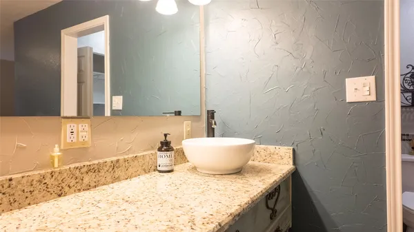 a bathroom with a granite countertop sink and a mirror