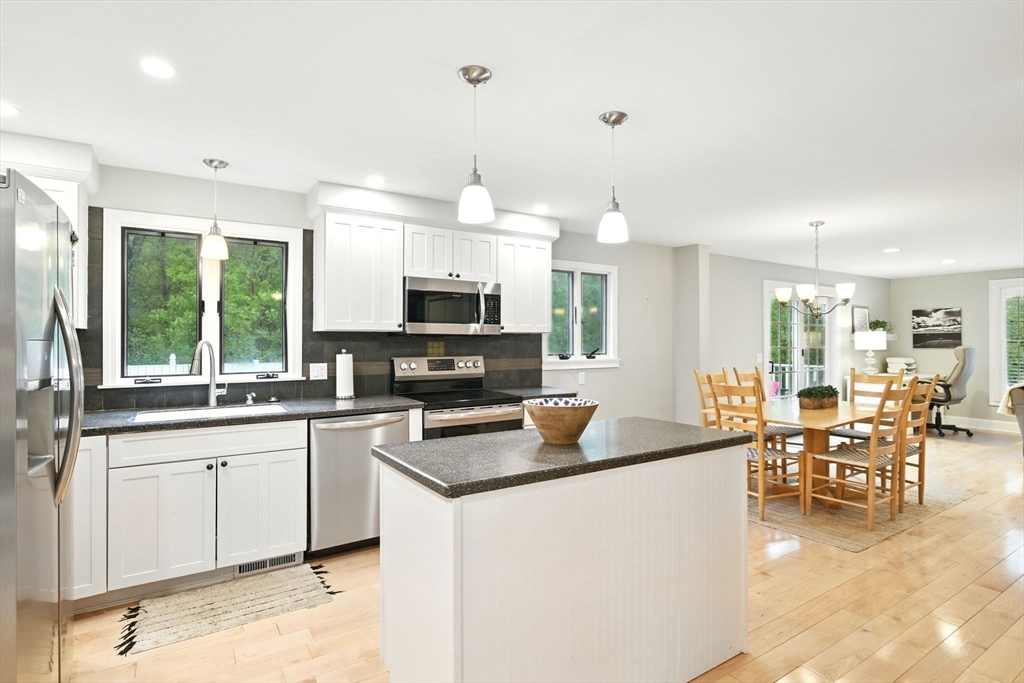 3 Pine Knoll Road Southwick, MA 01077 - Photo 11 of 42 a kitchen with stainless steel appliances granite countertop a stove top oven a sink a dining table and chairs with wooden floor