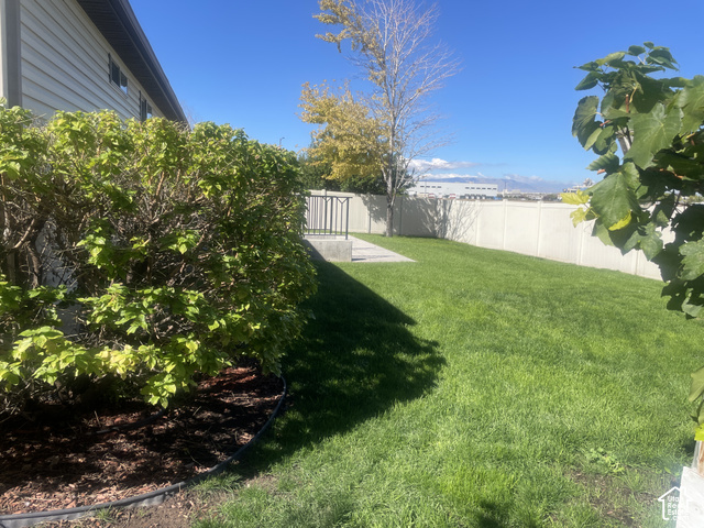 1706 Renaissance Way Springville, UT 84663 - Photo 6 of 31 Expansive backyard featuring a manicured lawn, mature landscaping with established shrubs and trees, and a white vinyl privacy fence