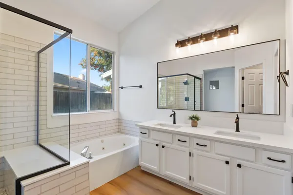 a bathroom with a tub a sink and mirror