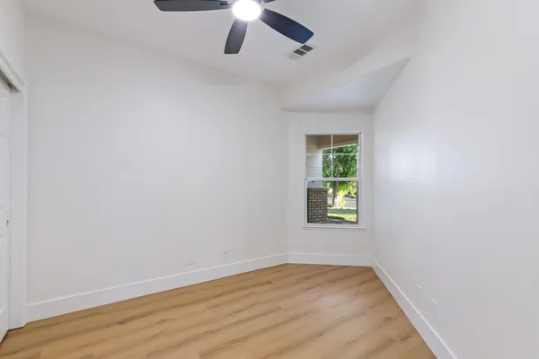 an empty room with a window and a ceiling fan
