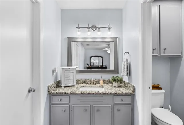 a bathroom with a granite countertop sink a toilet and a mirror