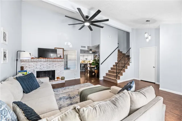a living room with furniture a fireplace and a ceiling fan