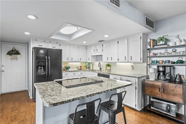 a kitchen with stainless steel appliances granite countertop a stove top oven a sink a refrigerator and white cabinets