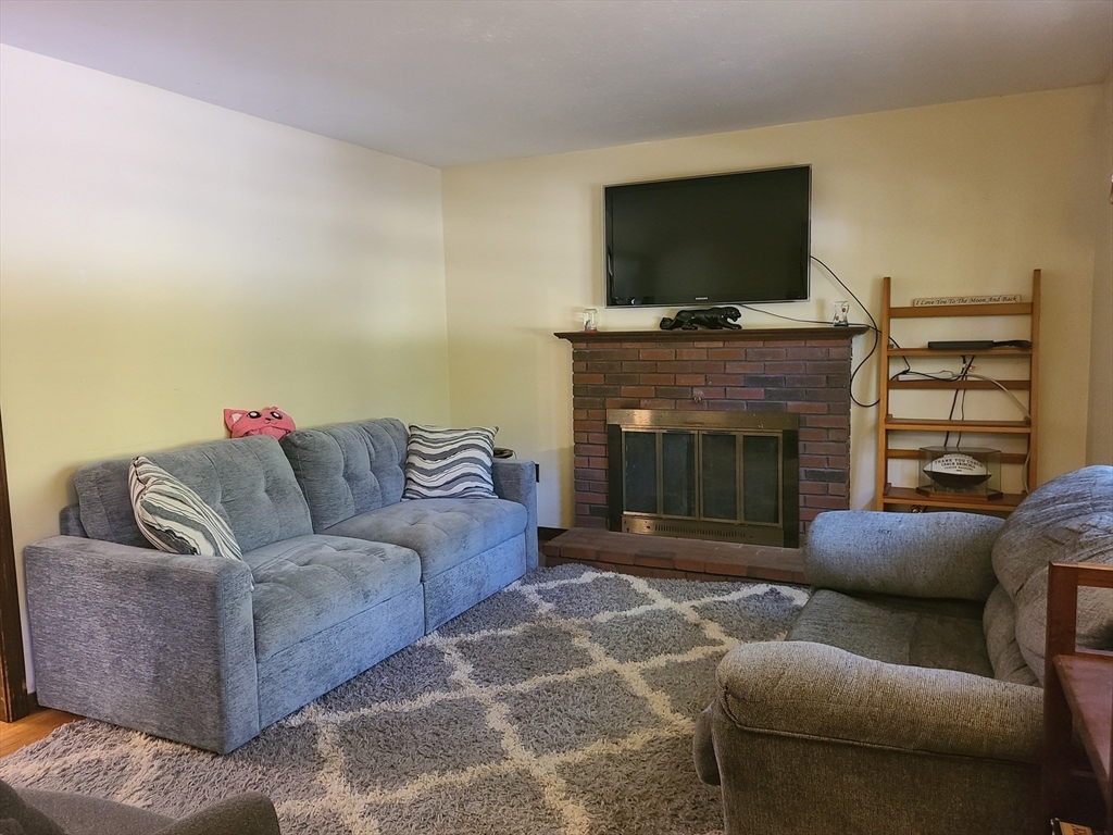 131 Holly Ridge Drive Hanson, MA 02341 - Photo 6 of 36 a living room with furniture a flat screen tv and a fireplace