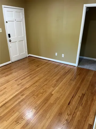 an empty room with wooden floor and white wall