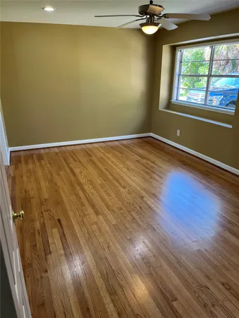 a view of empty room with wooden floor and fan