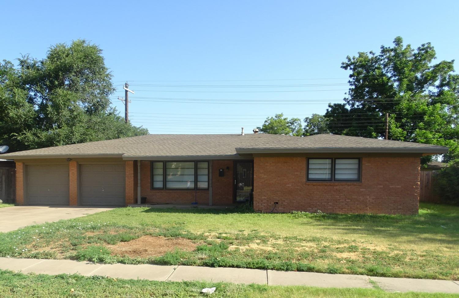 a view of a house with a yard plants and large tree