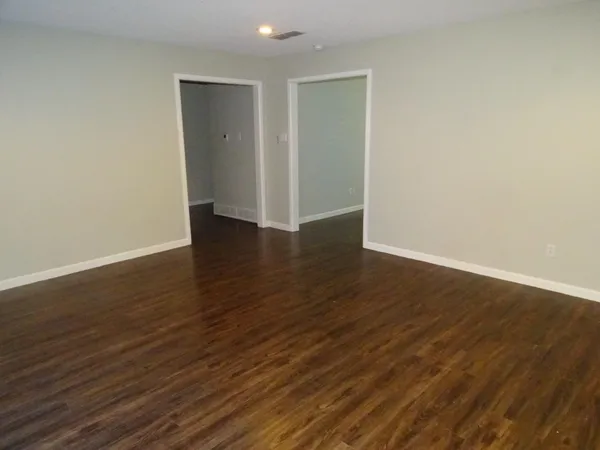 a view of an empty room with wooden floor and closet