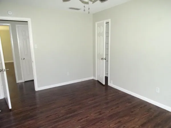 an empty room with wooden floor and a ceiling fan