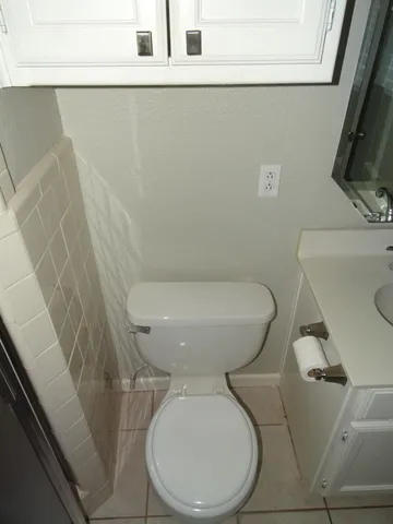 a white toilet sitting next to a white sink and vanity