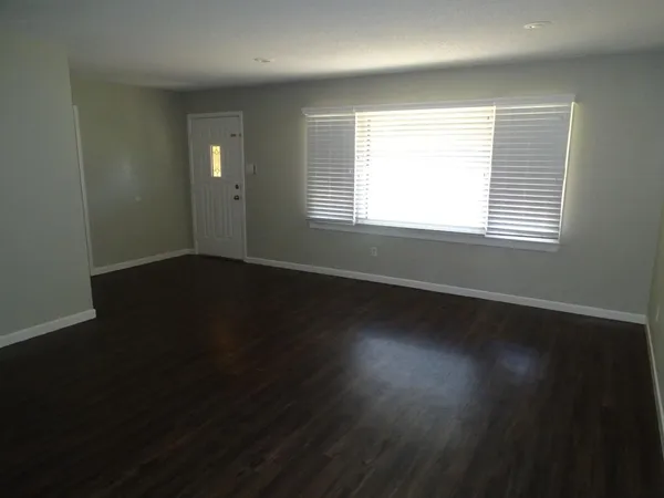 an empty room with wooden floor and windows in it
