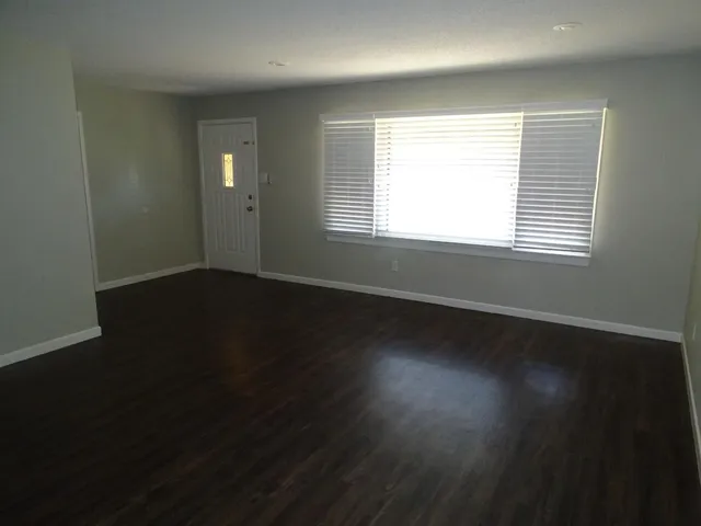 an empty room with wooden floor and windows in it
