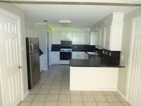 a living room with stainless steel appliances kitchen island granite countertop a refrigerator and a sink