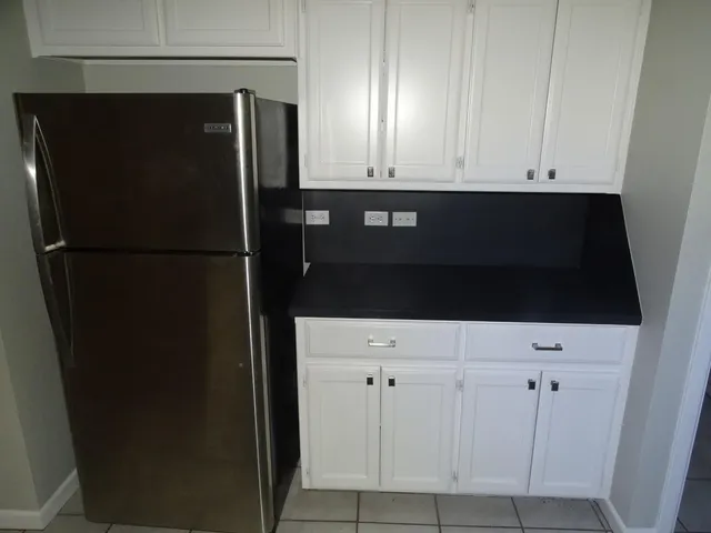 a view of kitchen with refrigerator and wooden cabinets