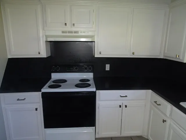 a kitchen with a stove and a white cabinets