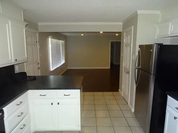 a kitchen with white cabinets and refrigerator