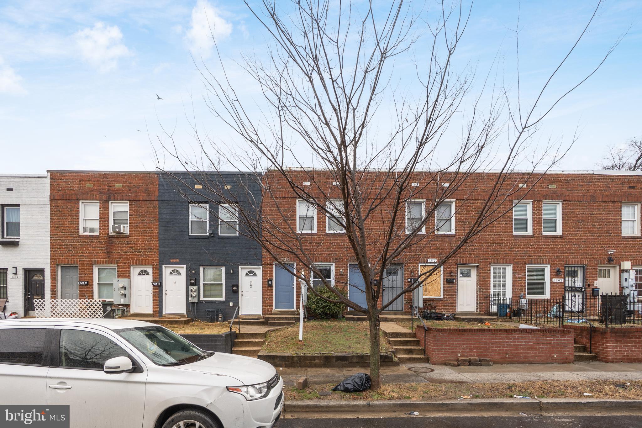 a front view of a building with lot of cars and trees