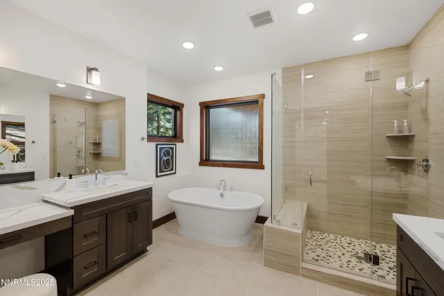 a bathroom with a double vanity sink a toilet a mirror and shower