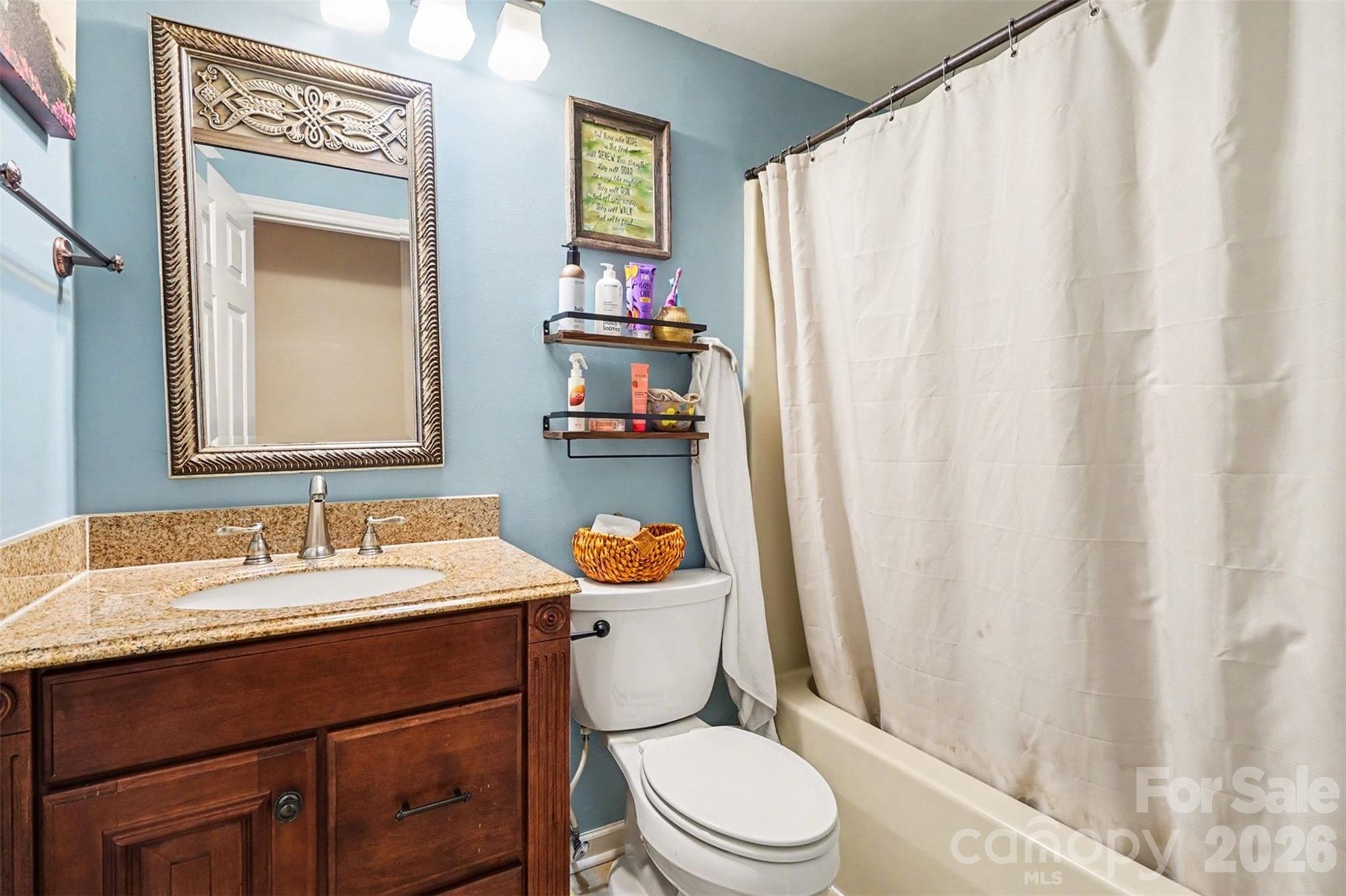 12213 Woodside Falls Road Pineville, NC 28134 - Photo 20 of 28 a bathroom with a sink a toilet and shower curtain