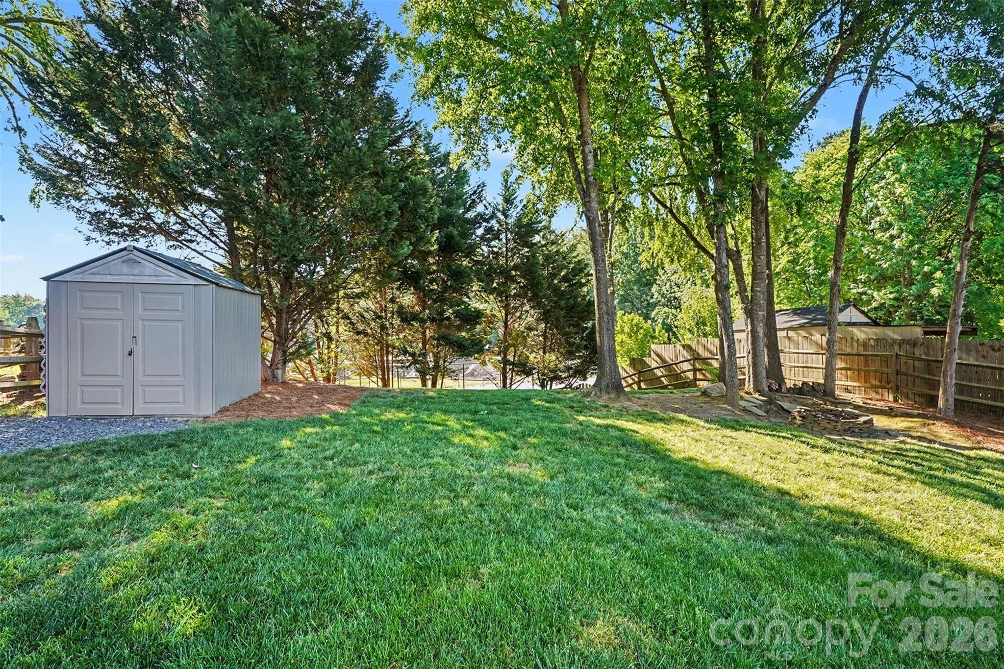 12213 Woodside Falls Road Pineville, NC 28134 - Photo 27 of 28 a view of a backyard with large trees and wooden fence