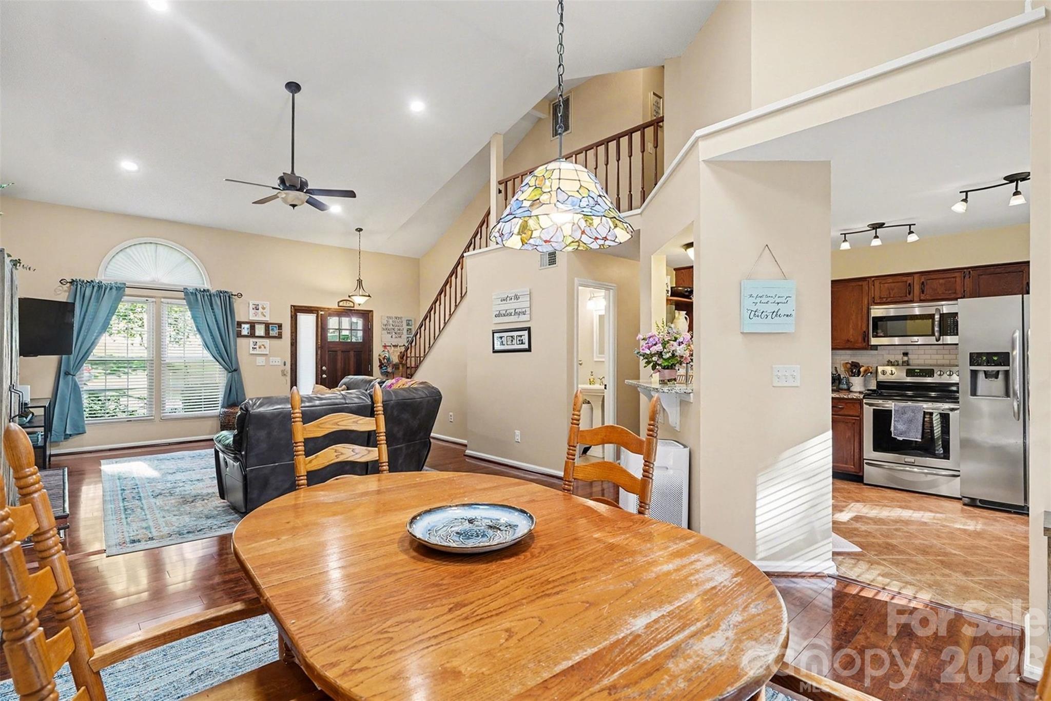 12213 Woodside Falls Road Pineville, NC 28134 - Photo 10 of 28 a kitchen with stainless steel appliances kitchen island granite countertop a stove a refrigerator a oven a dining table and chairs with wooden floor