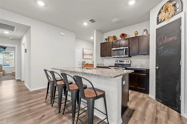 a kitchen with stainless steel appliances granite countertop a stove a refrigerator and a dining table with wooden floor