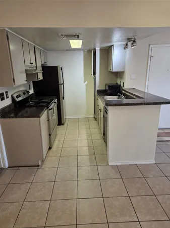 a kitchen with granite countertop a stove a sink and a refrigerator