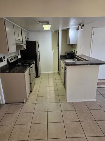 a kitchen with granite countertop a stove a sink and a refrigerator