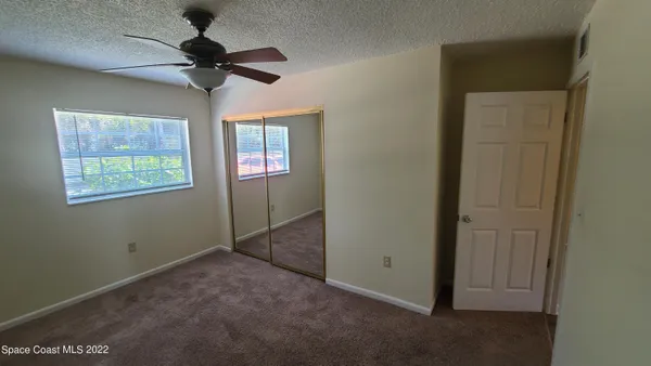 an empty room with windows and fan