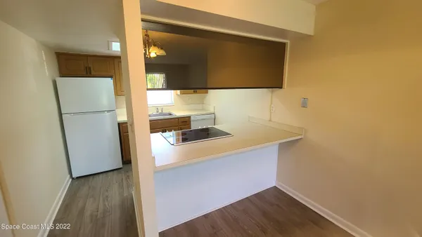a kitchen with a sink a refrigerator and wooden floor