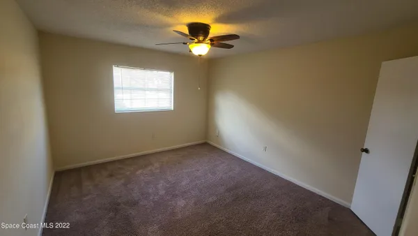 an empty room with window and a chandelier fan