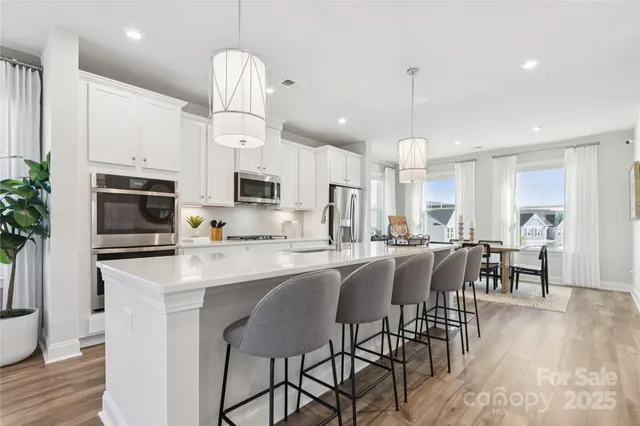 a kitchen with stainless steel appliances a dining table chairs stove a refrigerator and cabinets