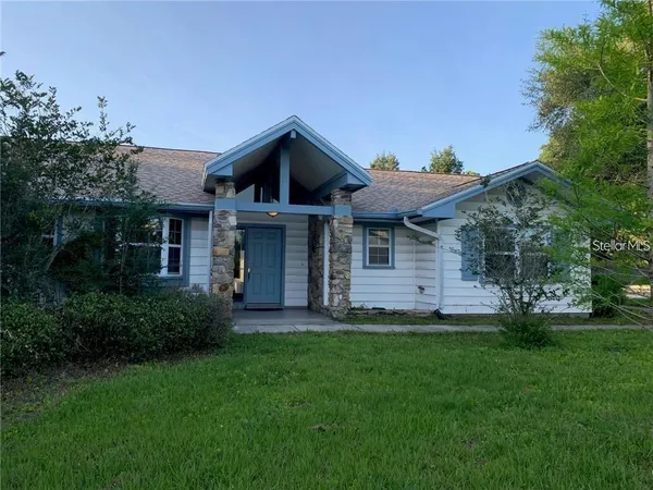 a front view of a house with a garden and trees
