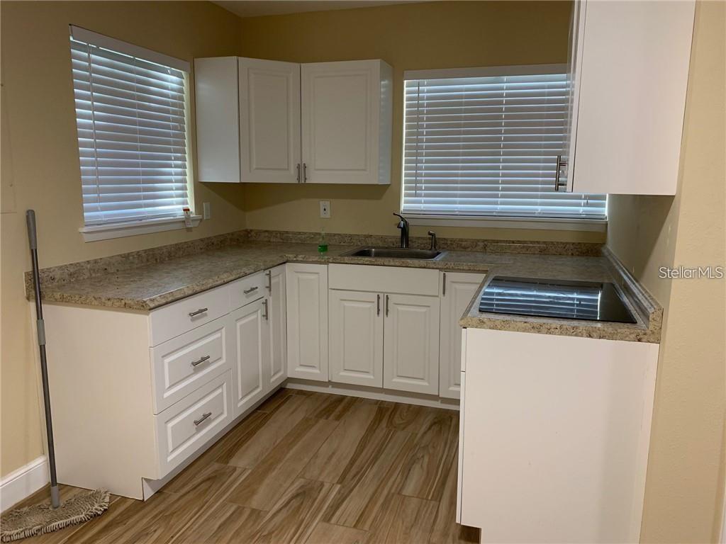 3090 Sunset Point Road Clearwater, FL 33759 - Photo 12 of 14 a kitchen with granite countertop white cabinets and white appliances