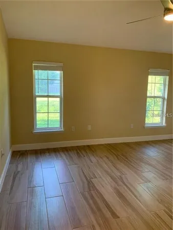 a view of an empty room and wooden floor and a window