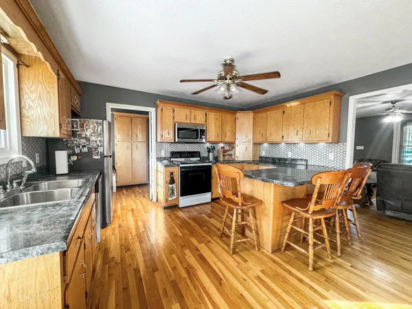 a kitchen with stainless steel appliances granite countertop a stove top oven a sink dishwasher a dining table and chairs with wooden floor