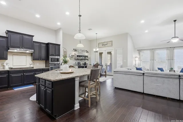 a kitchen with stainless steel appliances granite countertop a table chairs stove microwave and cabinets