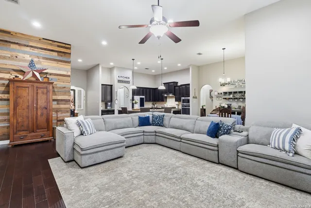 a living room with furniture kitchen view and a chandelier