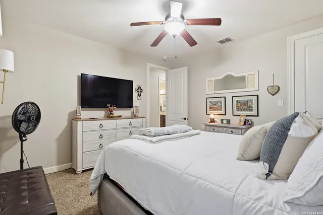 a bedroom with a bed a flat tv screen and a chandelier