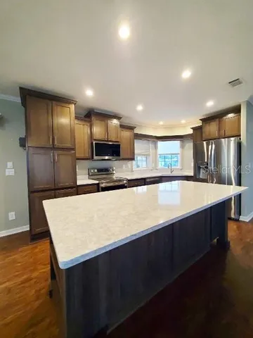 a kitchen with kitchen island a counter top space cabinets and stainless steel appliances