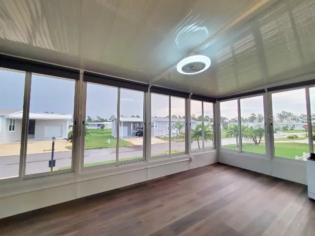 a view of an empty room with wooden floor and a window