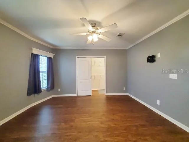 a view of an empty room with window and wooden floor