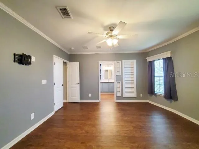 a view of an empty room with a window and wooden floor