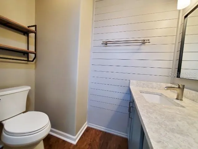 a bathroom with a granite countertop sink toilet and mirror