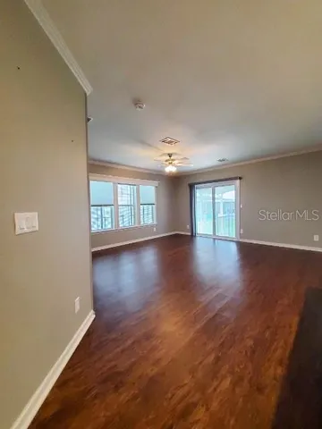 a view of an empty room with wooden floor and a window