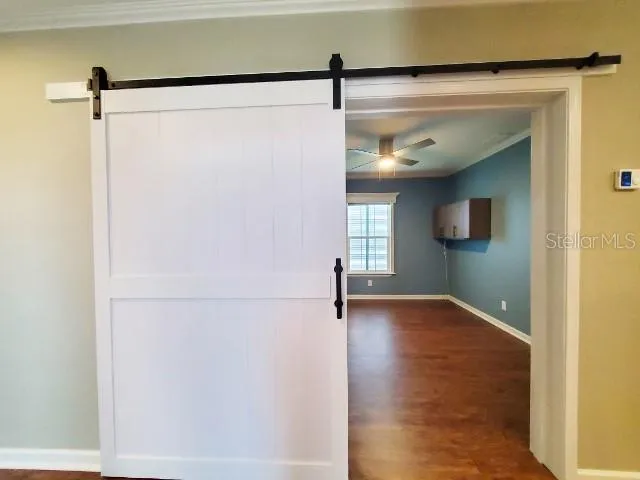 a view of empty room with wooden floor and fan