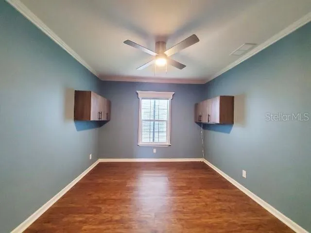 a view of empty room with wooden floor and fan