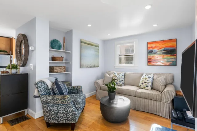 a living room with furniture potted plant and kitchen view