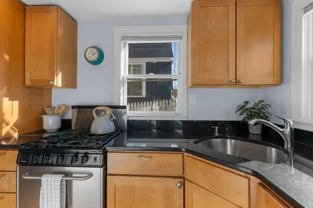 a kitchen with granite countertop a sink a stove and cabinets